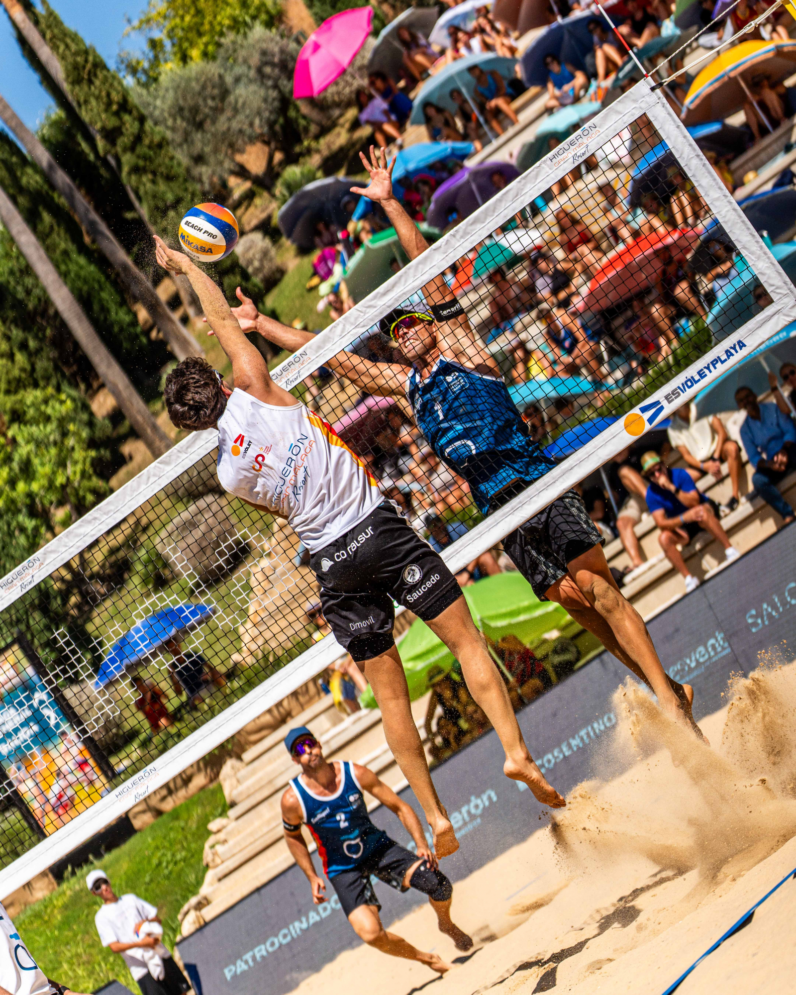 Antonio Saucedo attacking the hands of Alejandro Huerta's block and the watchful eye of Adrián Gavira waiting to defend in the semifinals of the Spanish Championship of Volleyo Playa 2025