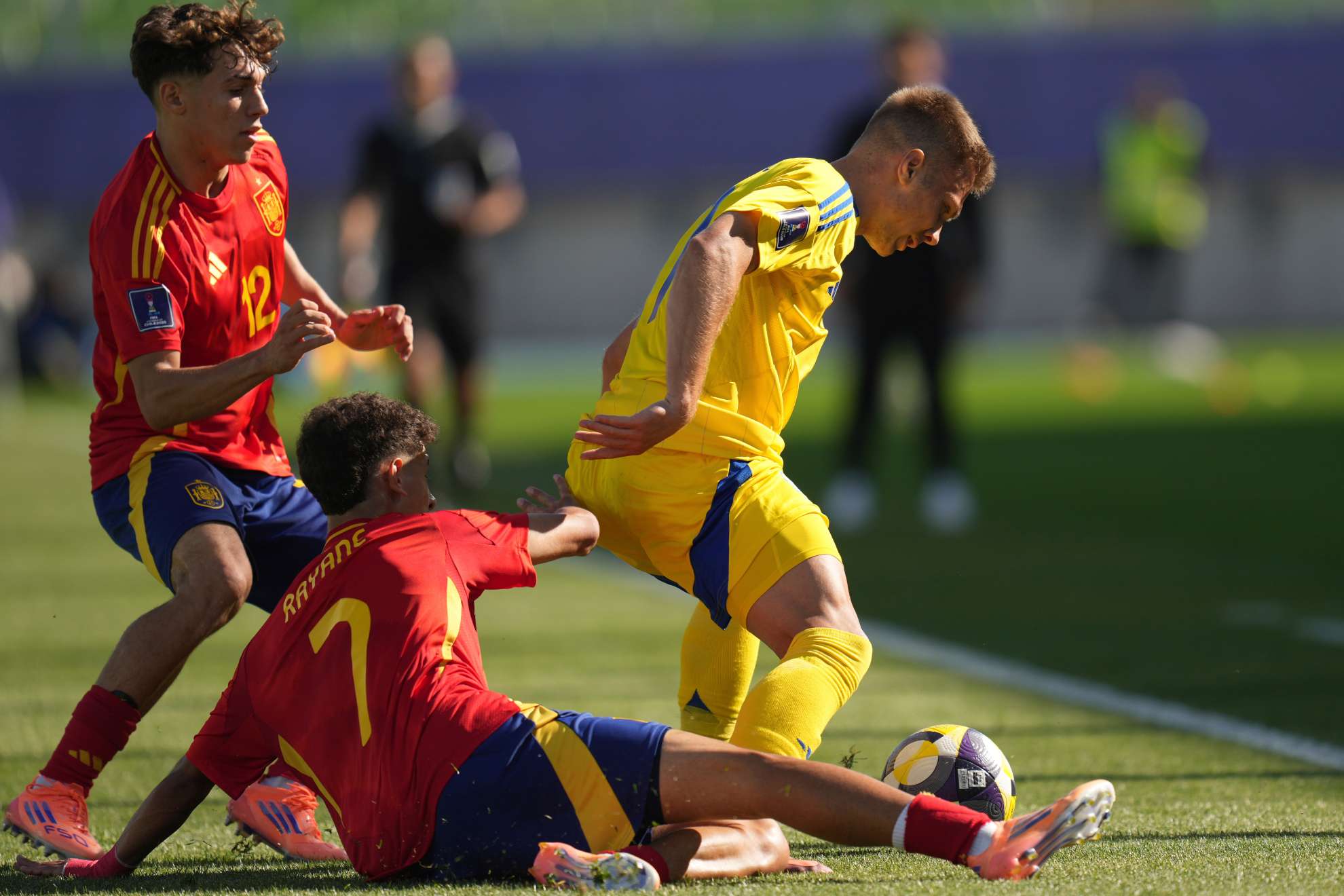 Rayane Belaid va al suelo para robar el balón a un jugador de Ucrania